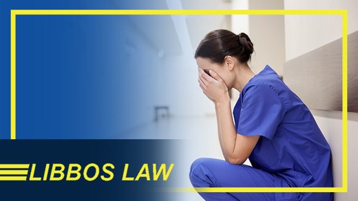 nurse sitting in a hallway with her hands in her face